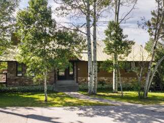 Nestled amongst mature trees, this charming home features a striking stone and wood exterior, complemented by a durable metal roof.