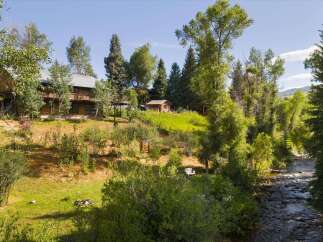 Nestled amidst lush greenery and mature trees, this property offers a serene retreat with a charming wooden lodge and a rustic cabin.