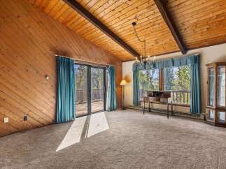 Experience rustic charm in this inviting living space featuring a vaulted wood-paneled ceiling and a cozy fireplace.