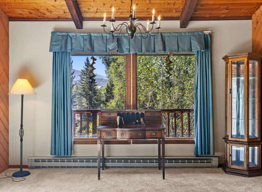 Experience breathtaking mountain views from this charming room, featuring a classic wooden desk and a beautiful glass display cabinet.