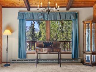 Experience breathtaking mountain views from this charming room, featuring a classic wooden desk and a beautiful glass display cabinet.
