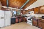 Discover a charming kitchen featuring warm wooden cabinetry and a vaulted wood-paneled ceiling with a decorative beam.