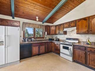 Discover a charming kitchen featuring warm wooden cabinetry and a vaulted wood-paneled ceiling with a decorative beam.