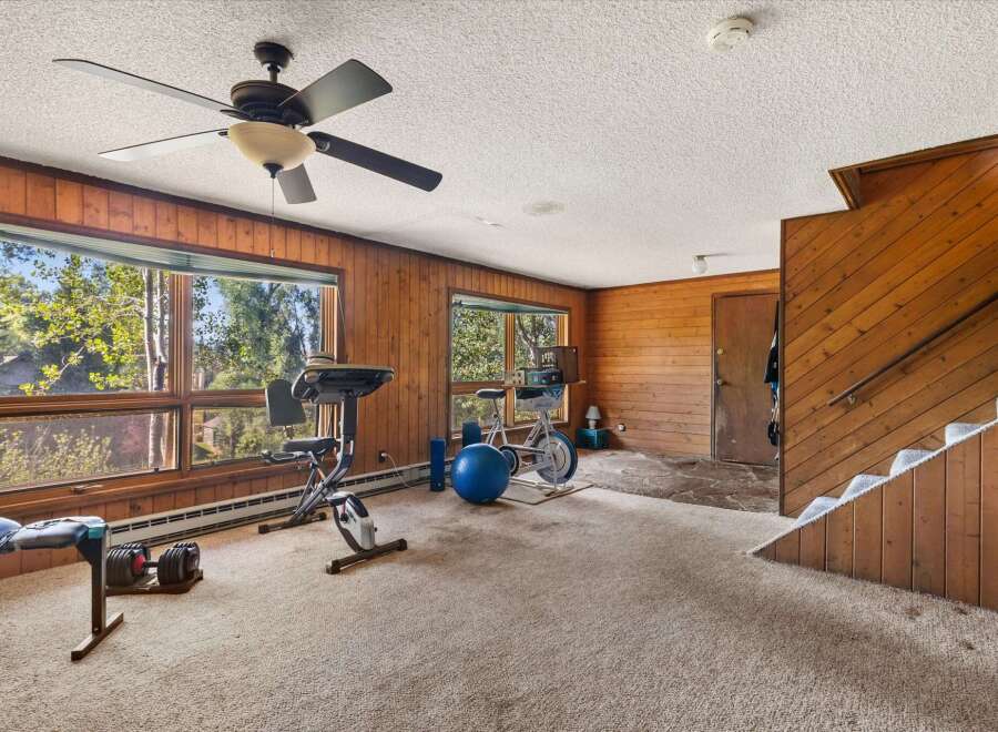 This spacious room features a home gym setup with a treadmill, stationary bike, and free weights, perfect for maintaining an active lifestyle.