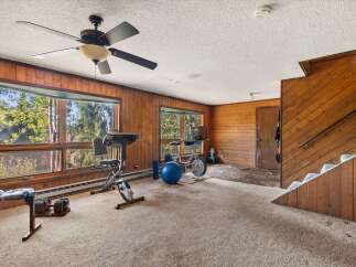 This spacious room features a home gym setup with a treadmill, stationary bike, and free weights, perfect for maintaining an active lifestyle.