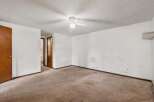 This spacious room features a neutral carpet and a white ceiling fan, perfect for creating a comfortable atmosphere.