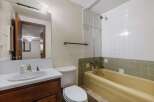 This bathroom features a classic yellow bathtub and a white sink with a vintage-style faucet.