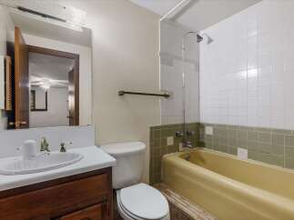 This bathroom features a classic yellow bathtub and a white sink with a vintage-style faucet.