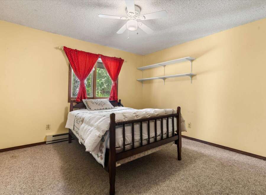 This charming bedroom features a cozy wooden bed adorned with a plush comforter and decorative pillows.