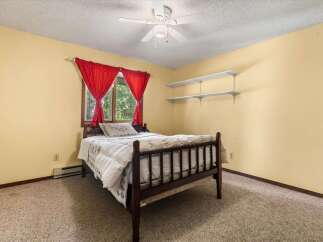 This charming bedroom features a cozy wooden bed adorned with a plush comforter and decorative pillows.