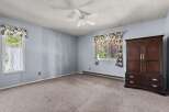 This spacious bedroom features a large window with floral curtains, allowing natural light to fill the room.