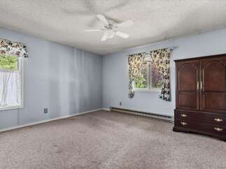 This spacious bedroom features a large window with floral curtains, allowing natural light to fill the room.