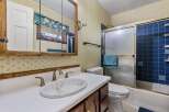 This bathroom features a charming floral wallpaper and a wooden vanity with a white countertop and sink.