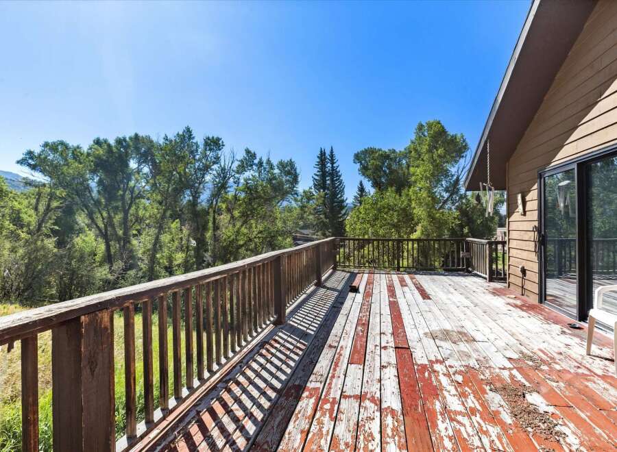Enjoy the serene natural surroundings from this spacious wooden deck, perfect for outdoor relaxation and entertaining.