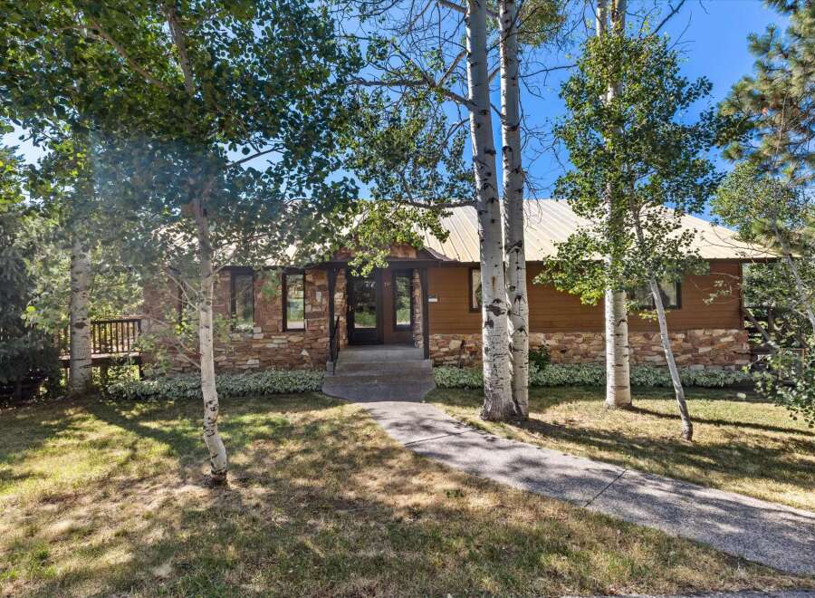 Nestled amongst mature trees, this charming home features a striking stone and wood exterior, complemented by a durable metal roof.