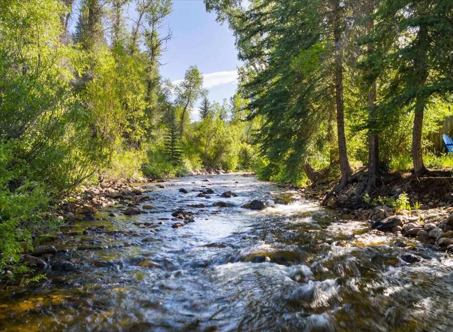 Experience the tranquility of this stunning property, featuring a picturesque river flowing through lush greenery.