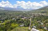 Discover this stunning aerial view of a picturesque mountain town nestled amidst lush green trees and rolling hills.