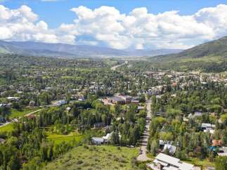 Discover this stunning aerial view of a picturesque mountain town nestled amidst lush green trees and rolling hills.
