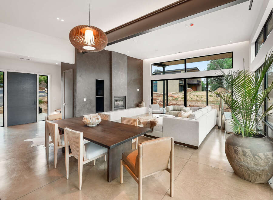 Experience modern luxury in this open-concept living space, featuring a striking fireplace and expansive windows that bring the outdoors in.