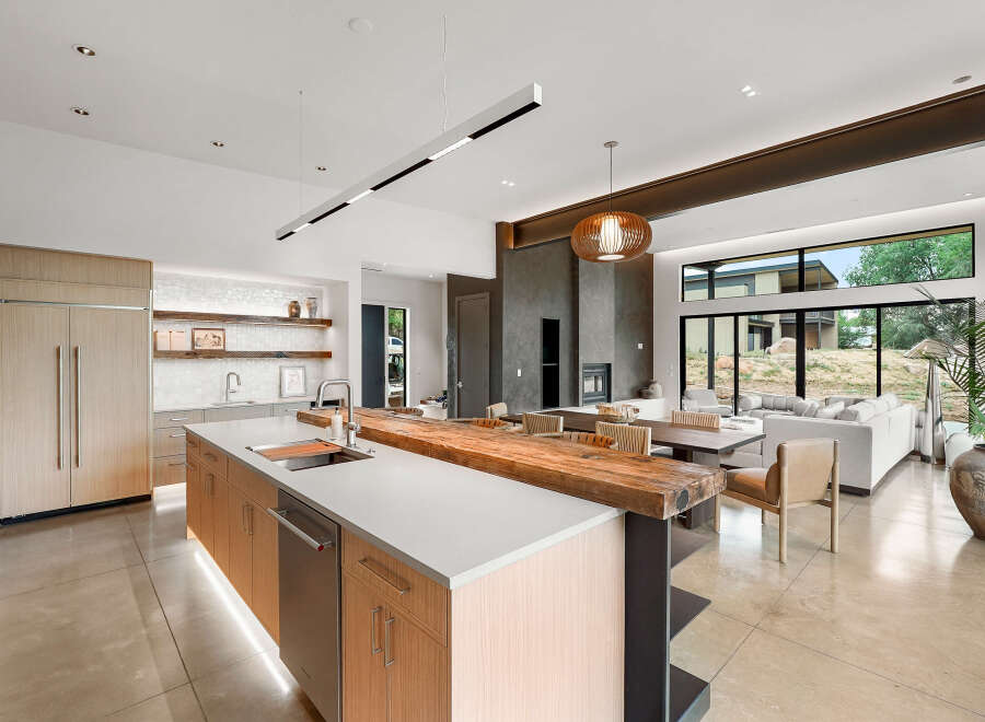 Experience modern luxury in this open-concept living space, featuring a sleek kitchen with integrated appliances and a stunning live-edge wood island.