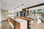 Experience modern luxury in this open-concept living space, featuring a sleek kitchen with integrated appliances and a stunning live-edge wood island.
