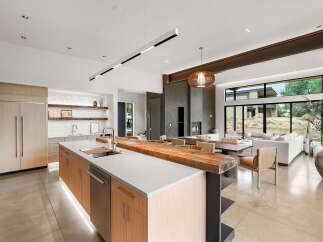 Experience modern luxury in this open-concept living space, featuring a sleek kitchen with integrated appliances and a stunning live-edge wood island.