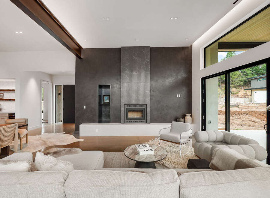 Experience modern luxury in this stunning living room, featuring a sleek fireplace with a dramatic dark stone surround and integrated shelving.