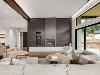 Experience modern luxury in this stunning living room, featuring a sleek fireplace with a dramatic dark stone surround and integrated shelving.