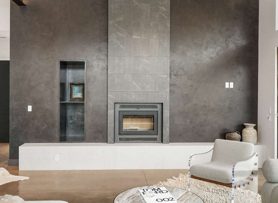 Experience modern luxury with this stunning living space featuring a sleek, textured gray fireplace as the focal point.