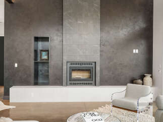 Experience modern luxury with this stunning living space featuring a sleek, textured gray fireplace as the focal point.