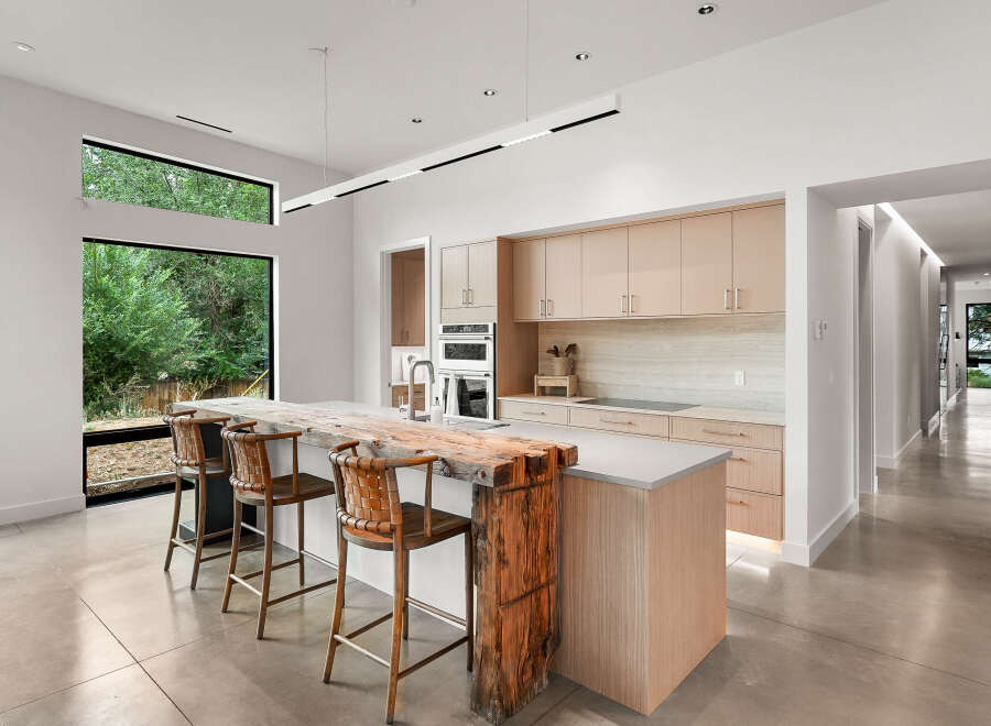 Experience modern luxury in this stunning kitchen featuring a live-edge wood island and sleek, light wood cabinetry.