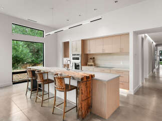 Experience modern luxury in this stunning kitchen featuring a live-edge wood island and sleek, light wood cabinetry.