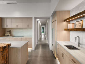 Experience modern luxury in this stunning kitchen featuring sleek, light wood cabinetry and a spacious island with a rustic wood accent.