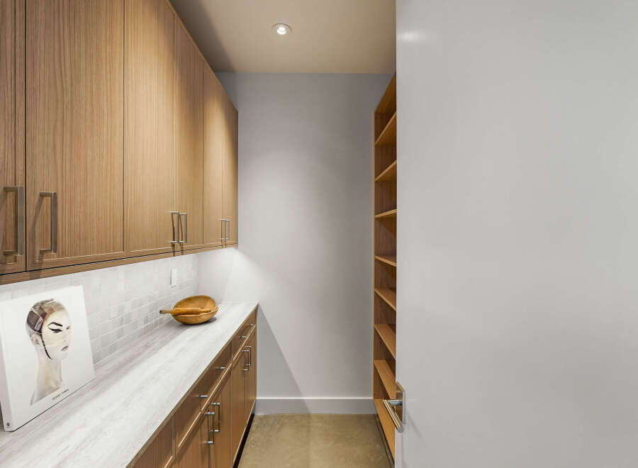 Discover this modern pantry featuring sleek, light wood cabinetry with brushed nickel hardware.