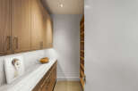 Discover this modern pantry featuring sleek, light wood cabinetry with brushed nickel hardware.