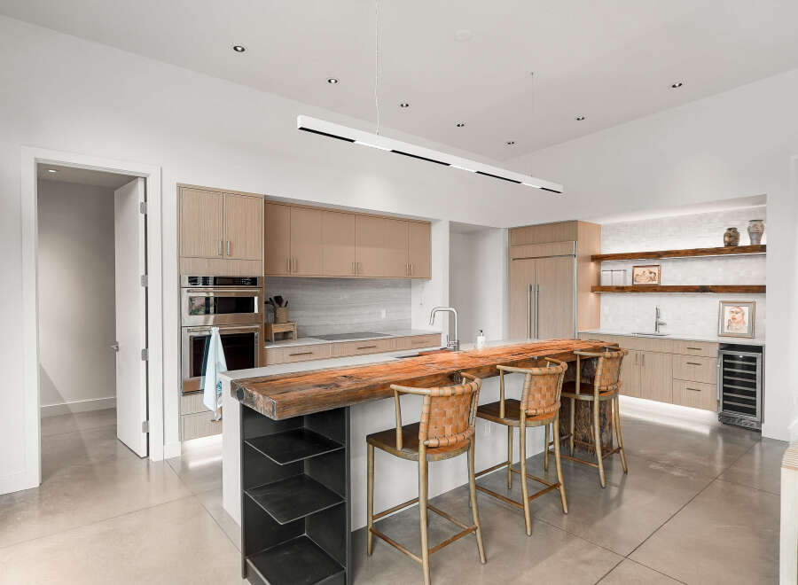 Experience luxury living in this modern kitchen featuring sleek, light wood cabinetry and a stunning live-edge wood island.