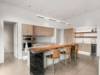 Experience luxury living in this modern kitchen featuring sleek, light wood cabinetry and a stunning live-edge wood island.