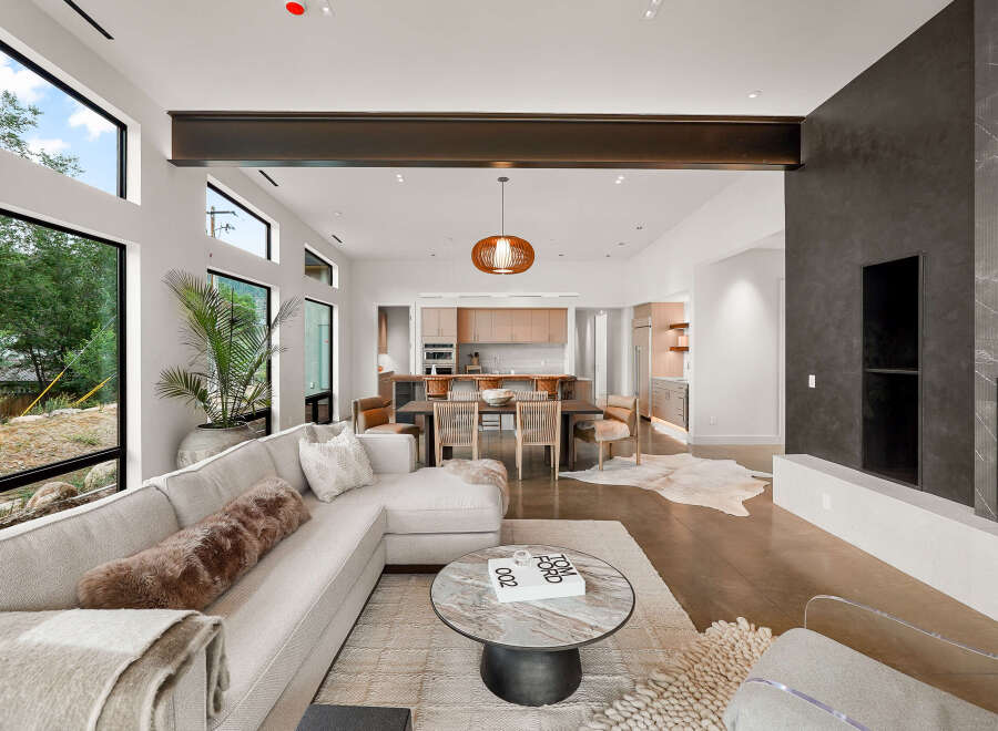 Experience modern luxury in this open-concept living space, featuring a sleek sectional sofa and a striking dark stone fireplace.