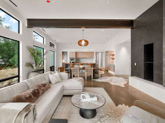 Experience modern luxury in this open-concept living space, featuring a sleek sectional sofa and a striking dark stone fireplace.