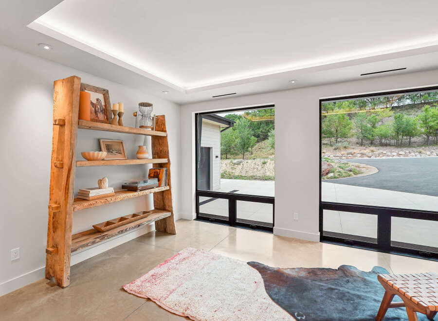 Experience modern living with expansive windows framing lush greenery and a scenic driveway.