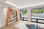 Experience modern living with expansive windows framing lush greenery and a scenic driveway.