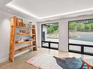 Experience modern living with expansive windows framing lush greenery and a scenic driveway.