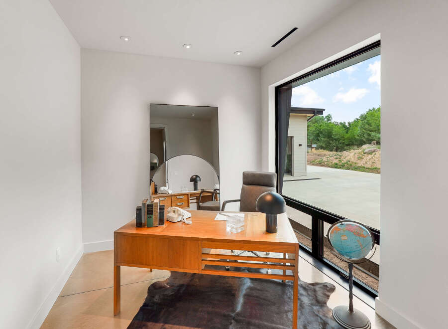 This modern office space features a sleek wooden desk complemented by a vintage telephone and a classic globe, creating a sophisticated workspace.