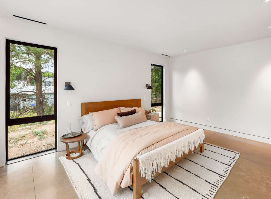 Experience modern comfort in this serene bedroom, featuring a plush bed adorned with soft, neutral-toned linens and accent pillows.