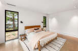 Experience modern comfort in this serene bedroom, featuring a plush bed adorned with soft, neutral-toned linens and accent pillows.