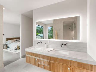 Experience modern luxury in this master bathroom featuring a sleek double vanity with marble countertops and integrated sinks.