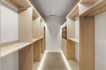 Step into this spacious walk-in closet, featuring custom light wood shelving and ample hanging space.