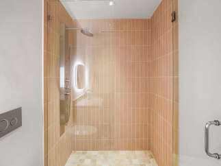Experience modern luxury in this stunning bathroom featuring a spacious walk-in shower with elegant peach-toned vertical tiles.