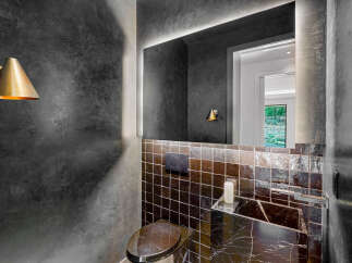 Experience modern luxury in this stylish powder room, featuring a sleek marble vanity and a unique mosaic tile backsplash.