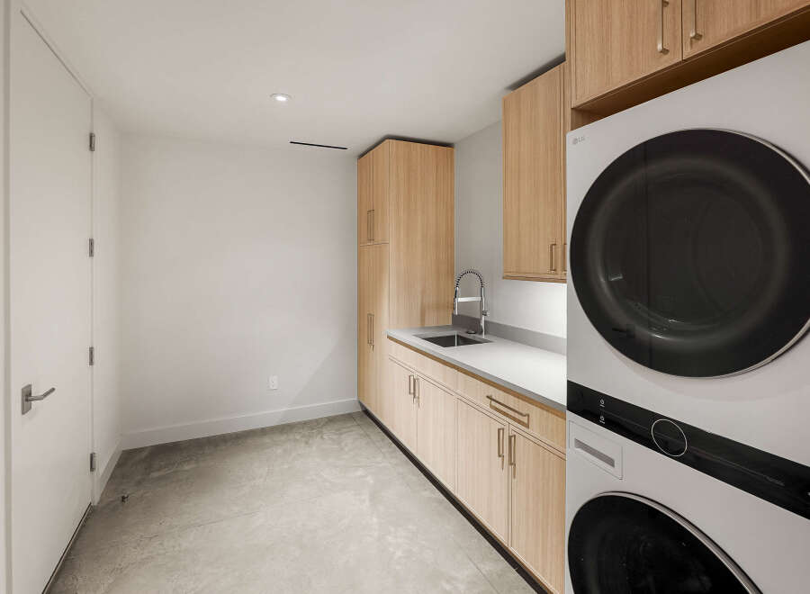This modern laundry room features sleek, light wood cabinetry providing ample storage space.